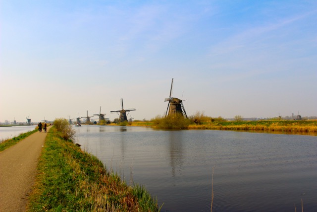 Saying goodbye to Kinderdijk windmills, a few from afar with the windmills in the distance and the water in front 