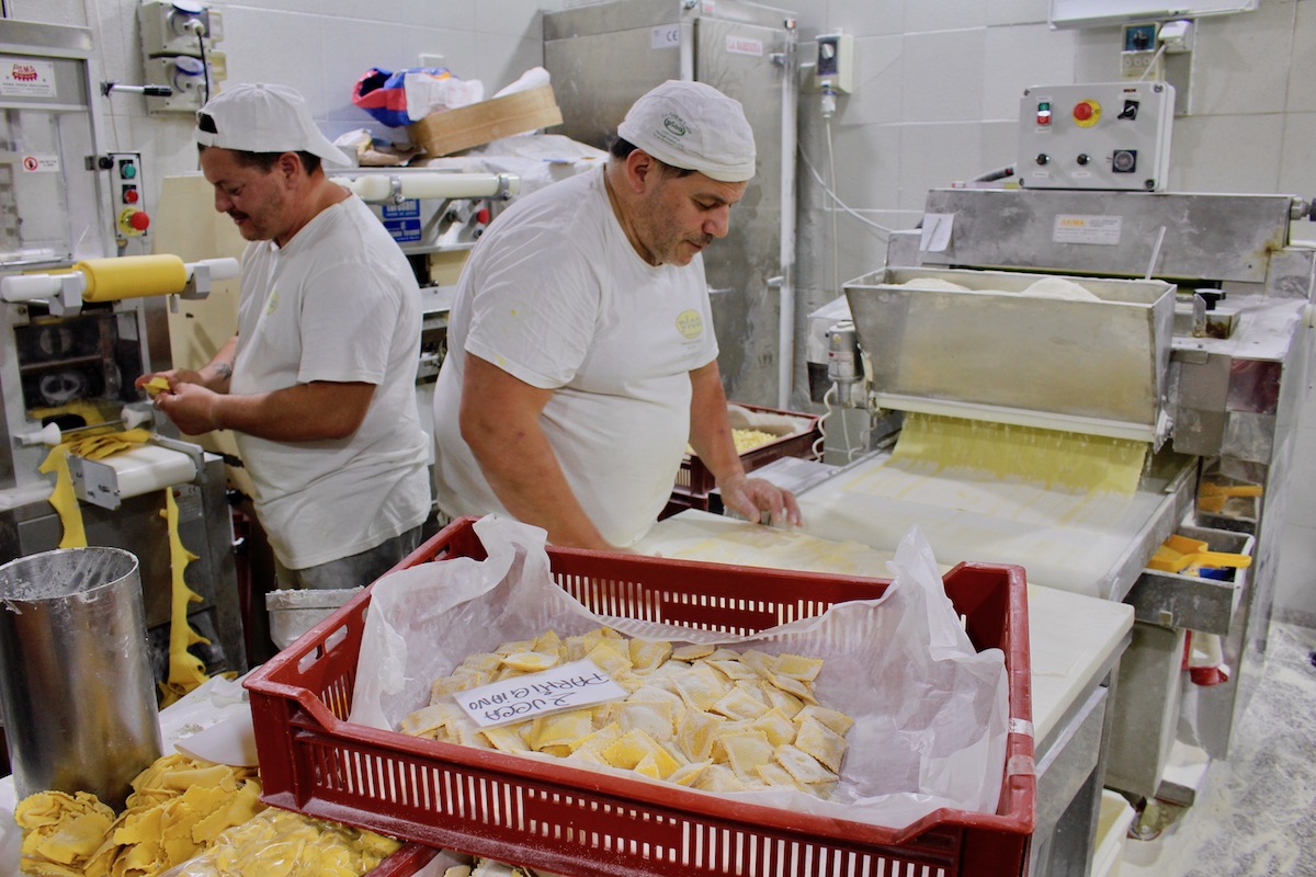 Two pasta makers working back to back in the warm factory