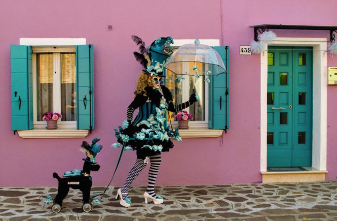 A women dressed in costume pulling a fake dog on a leash in Burano, Italy