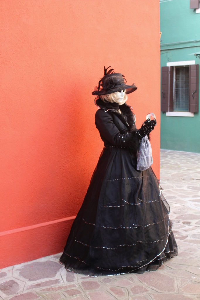 A woman with a crystal ball posing for her Carnival photoshoot in Burano, Italy