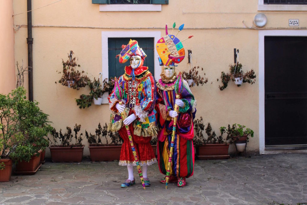 A very colorful couple dressed in traditional Venetian costumes in Burano, Italy