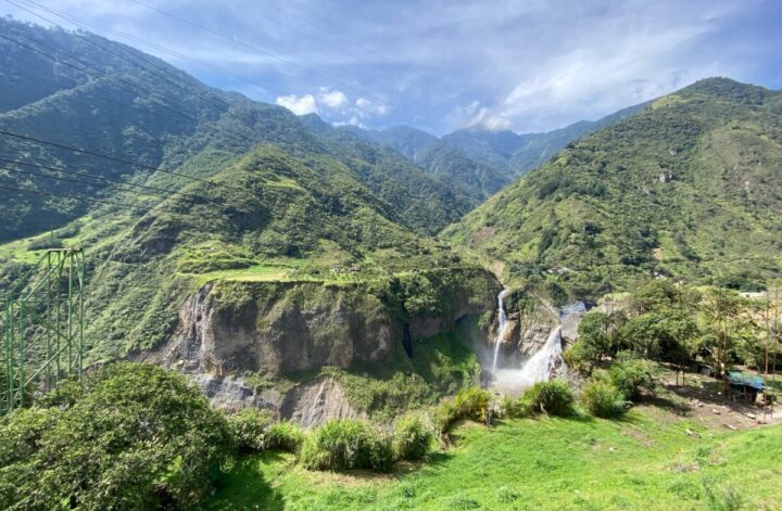At the start of the Ruta de las Cascadas, the first waterfall is in the distance surrounded by green land and cloudy skies