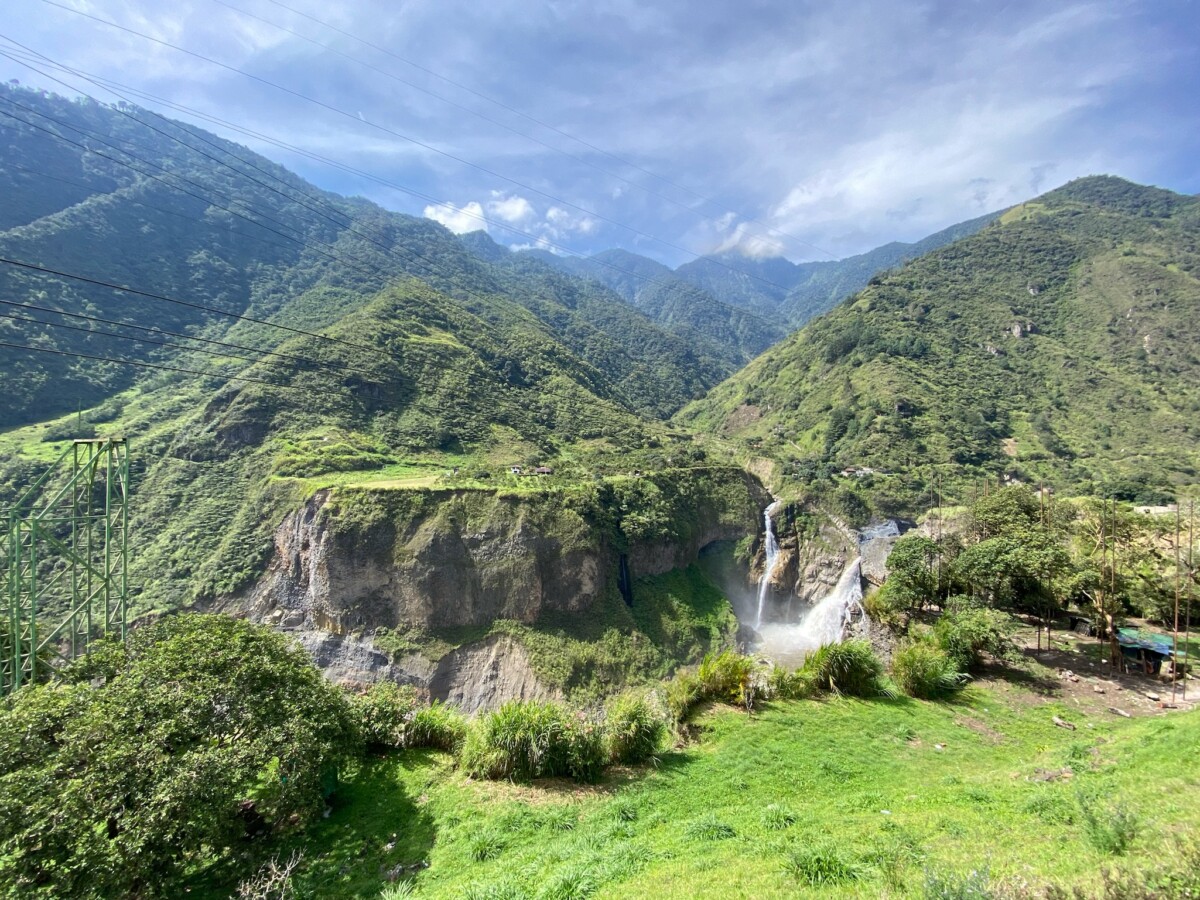 At the start of the Ruta de las Cascadas, the first waterfall is in the distance surrounded by green land and cloudy skies