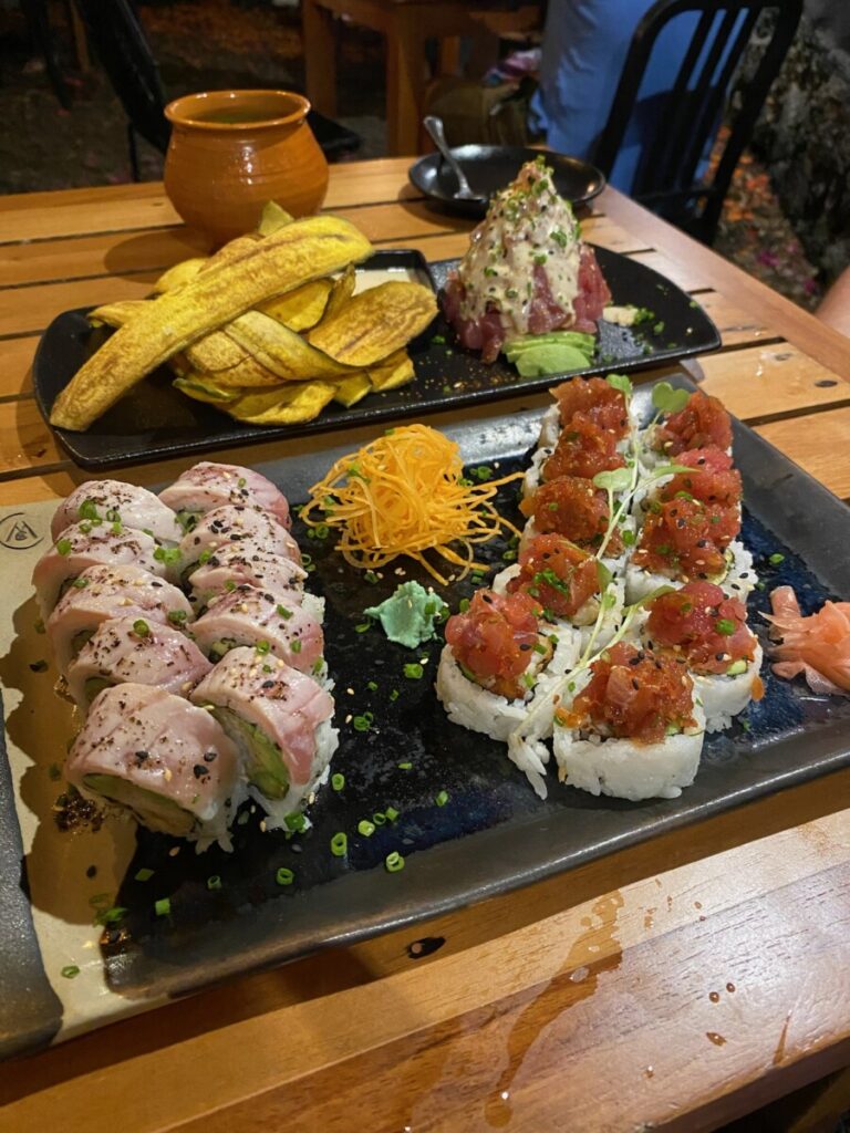 A plate with 2 sushi rolls and behind that tuna tataki with plantains. Where to eat in Puerto Ayora, best sushi. 