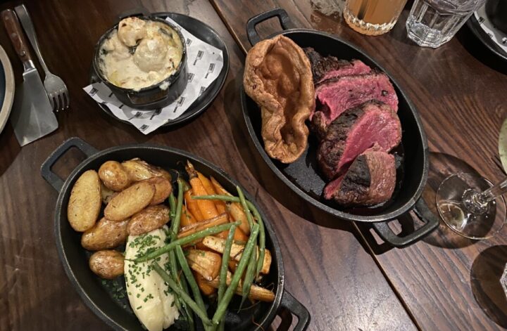 The beautiful Sunday Roast at Chateau X, a plate of meat, yorkshire pudding and a separate plate of sides and cauliflower