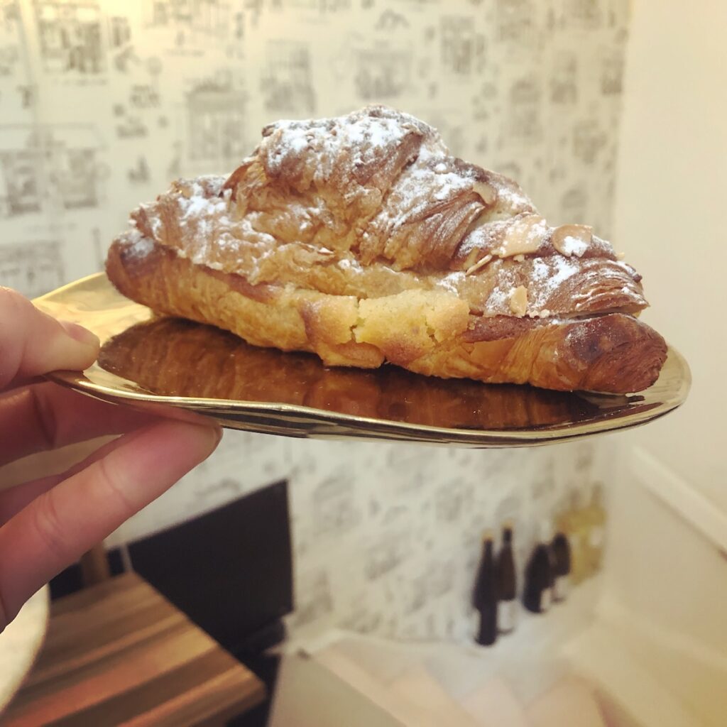 An almond croissant held in the air at one of the best cafes in Jordaan