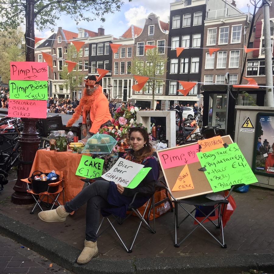 A girl selling drinks and cake on King's Day in Amsterdam