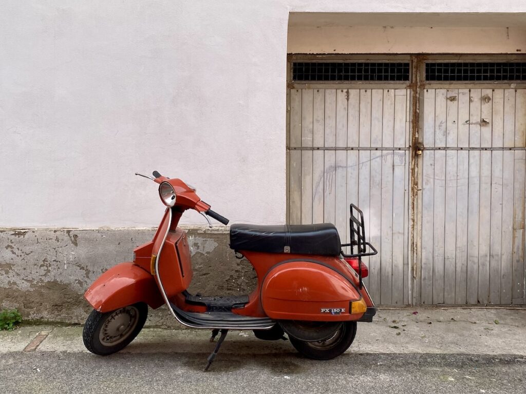 A red vespa on the road in Procida, Italy