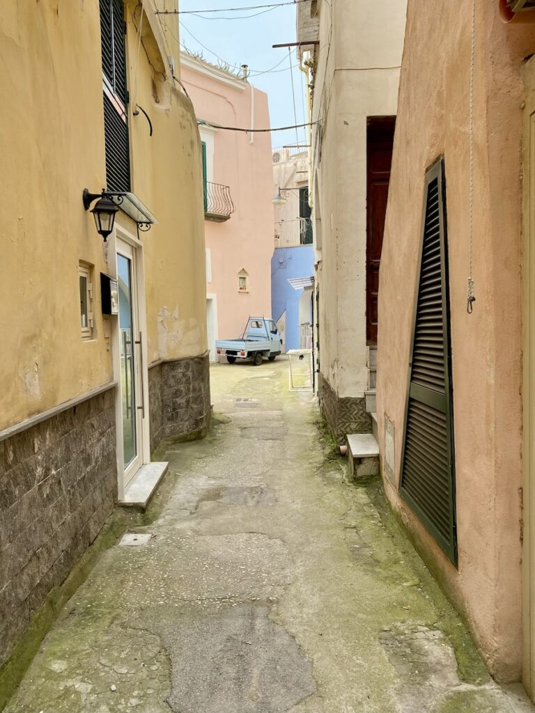 A dead end road with a small blue truck at the end 